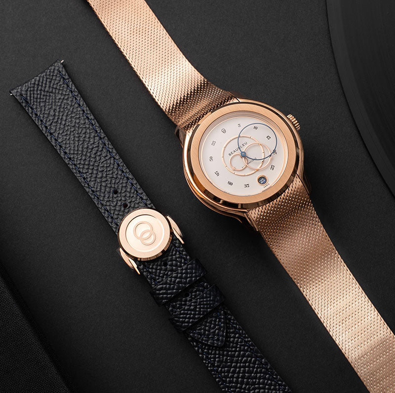 Montre Beaubleu Ecce Lys avec bracelet en acier or rose, posée à côté d'un bracelet en cuir noir grainé
