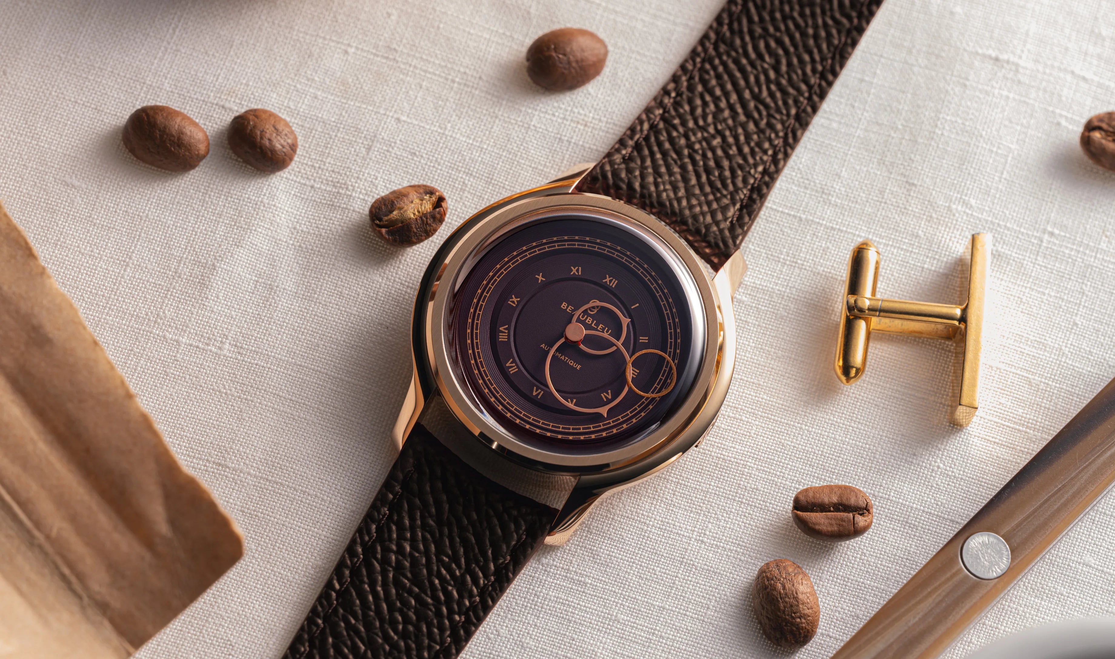 Montre La Pièce Moka de Beaubleu cadran marron posée sur une nappe blanche avec des grains de café