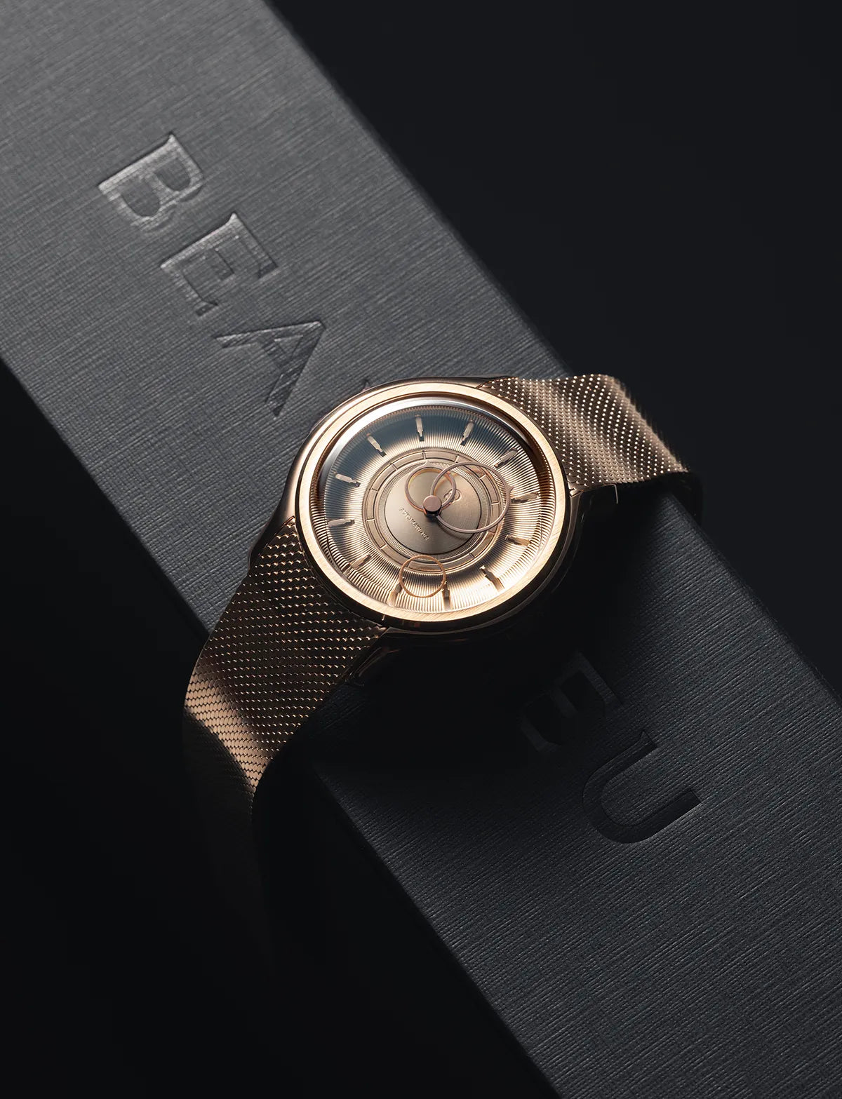 La Pièce Or Rose avec un bracelet maille métallique posée sur un coffret noir de la marque Beaubleu