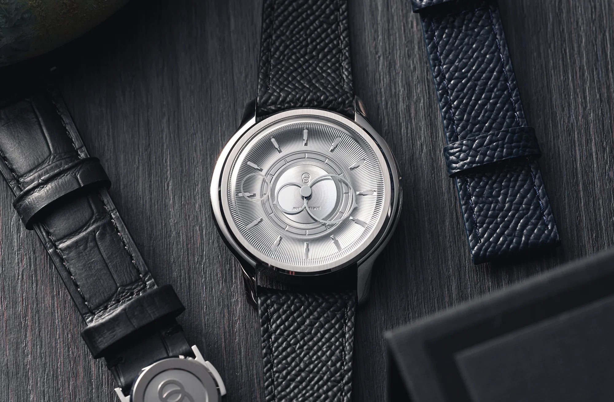 Montre La Pièce Argent de Beaubleu cadran acier posée à côté de bracelets en cuir