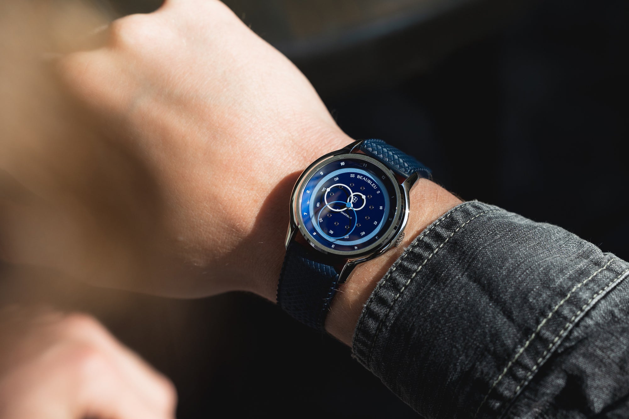 Montre Vitruve GMT Bleu avec un bracelet Tropic bleu portée au poignet d'un homme